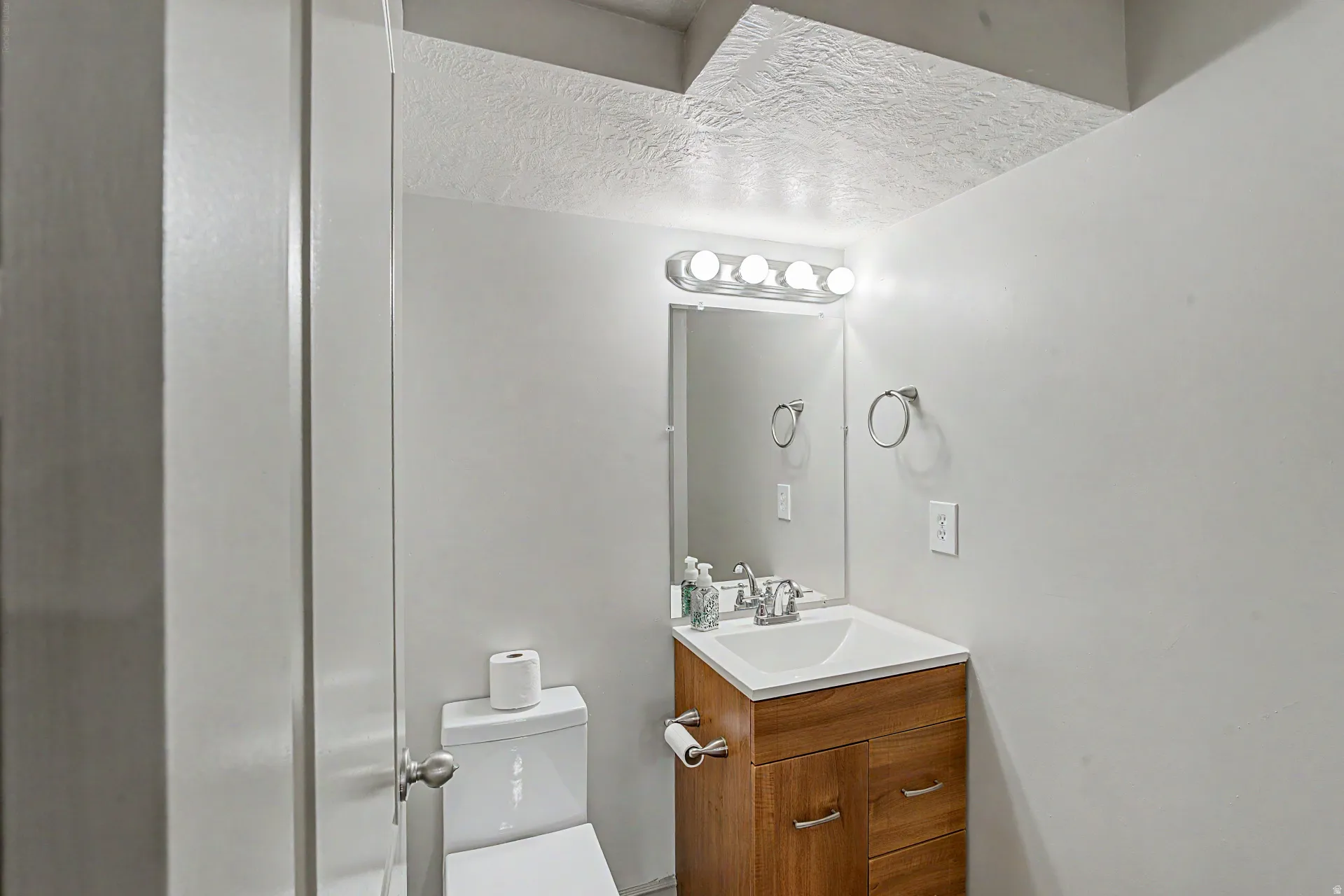 Half bath featuring vanity with mirror and updated lighting fixture