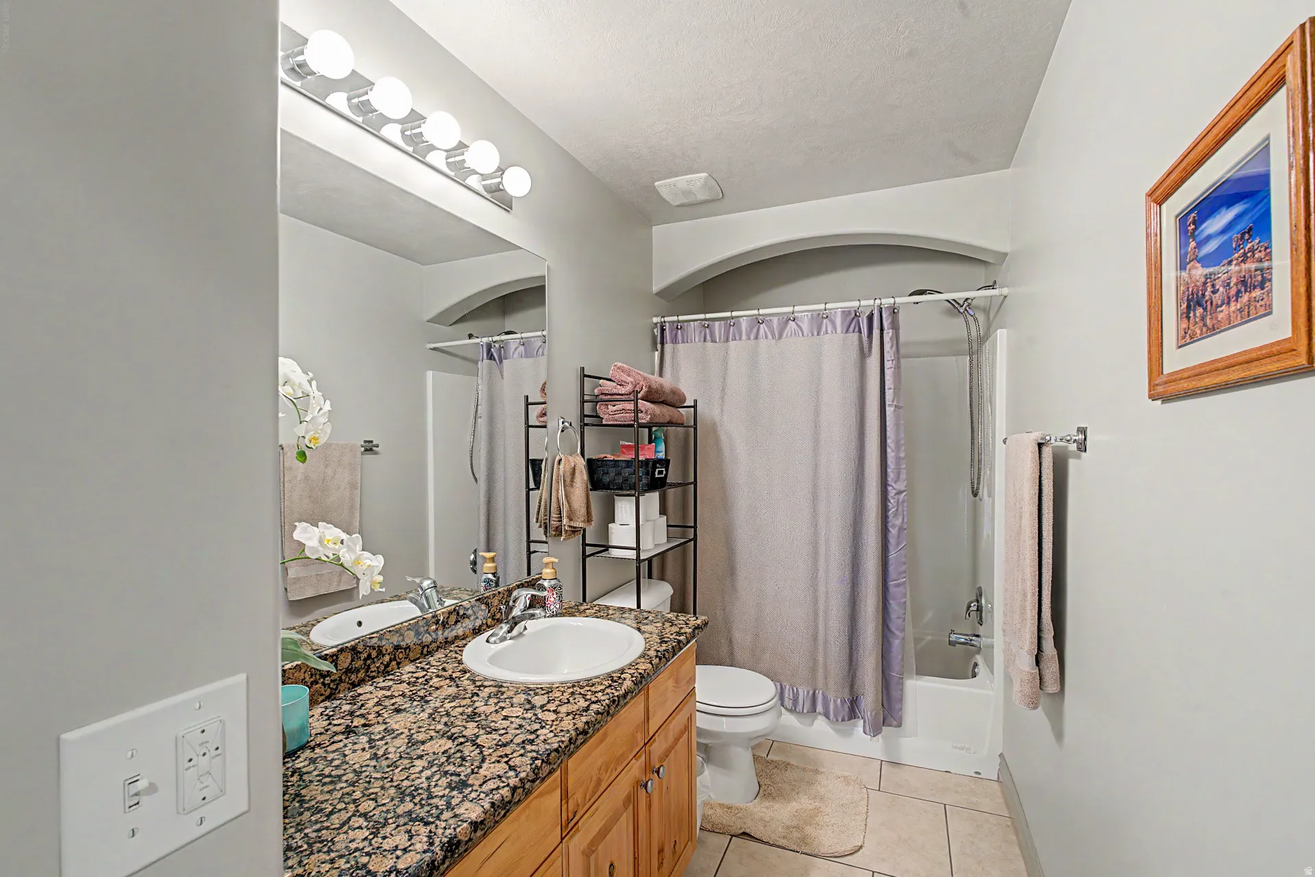 Bathroom with vanity, light tile patterned floors, shower / bathtub combination with curtain