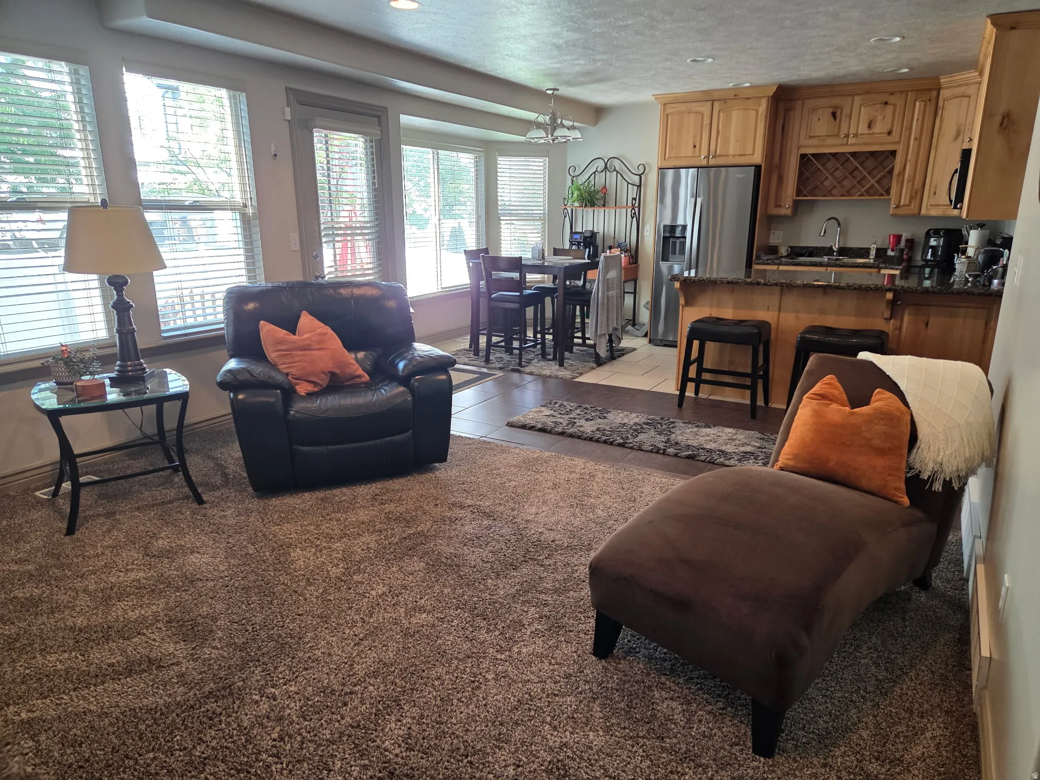 Open-concept living area featuring a kitchen with light wood cabinetry, a built-in wine rack, and a dark stone-finish countertop
