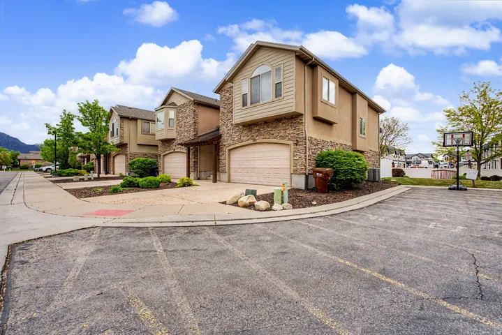 Traditional-style house with stone siding, an attached garage, stucco siding, concrete driveway, and a residential view