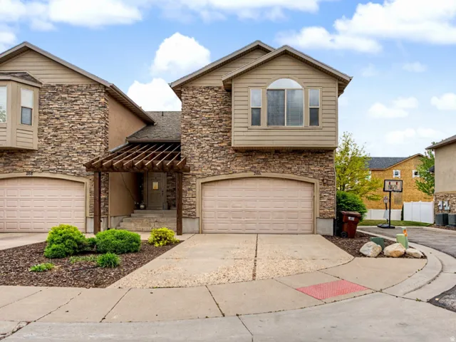 View of front of home featuring stone siding, an attached garage, and driveway