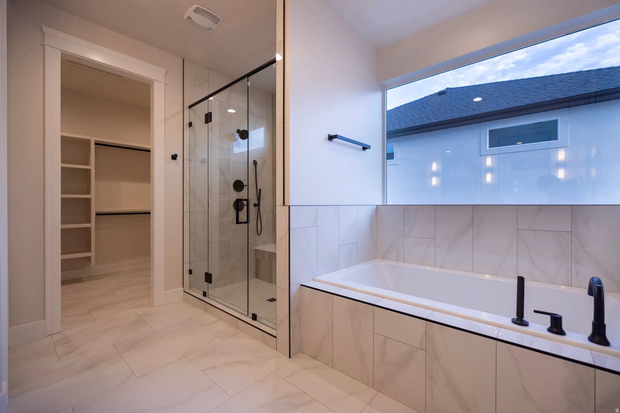 Master Bathroom featuring a dual shower head shower, a seperate bath, and a walk in closet