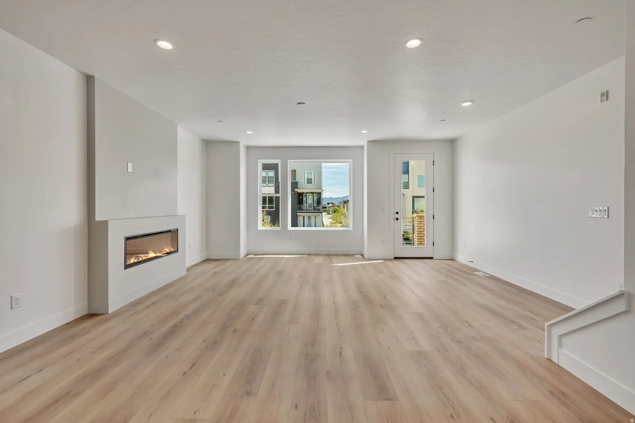 Unfurnished living room featuring a glass covered fireplace, light wood-style flooring, and recessed lighting