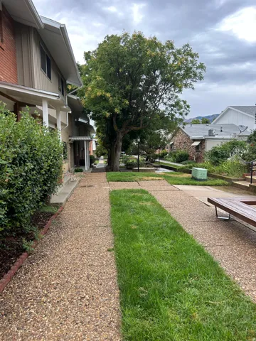 Expansive outdoor walkway featuring aggregate concrete pavers, grass strips, and established landscaping