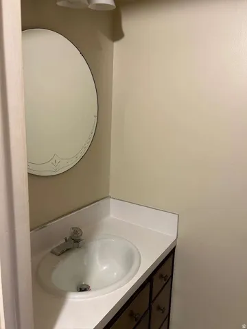 Vanity with integrated sink, white countertop, and dark wood-finish cabinetry featuring multiple drawers