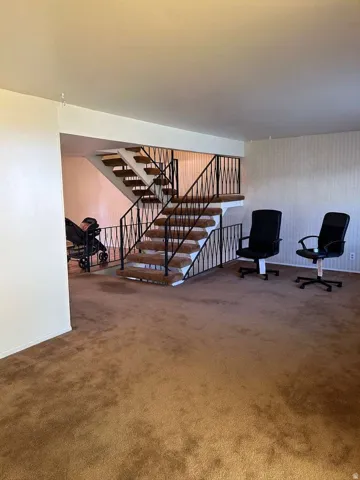 Two-story interior featuring a carpeted staircase with wrought iron railings