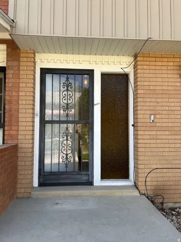 Brick exterior featuring a security screen door with decorative wrought ironwork, a textured glass entry door, and a covered concrete stoop