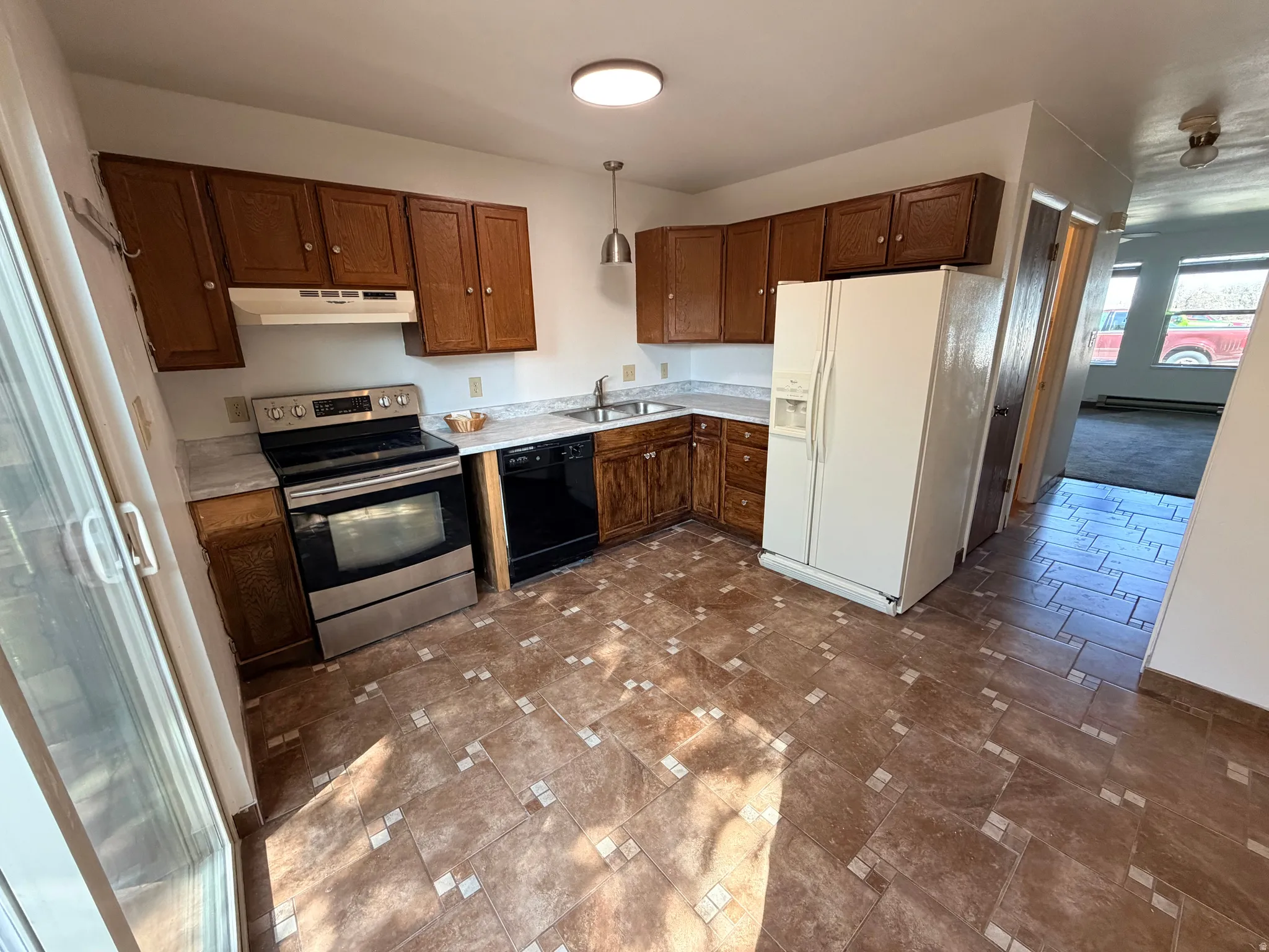 Kitchen featuring white refrigerator with ice dispenser, light countertops, stainless steel electric range, hanging light fixtures, and black dishwasher