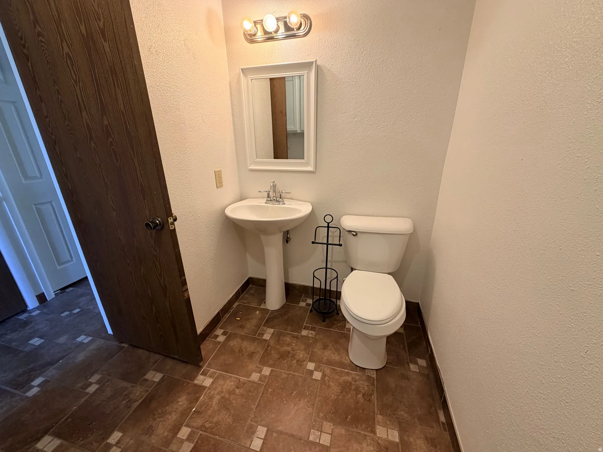 Half bath with a textured wall and toilet