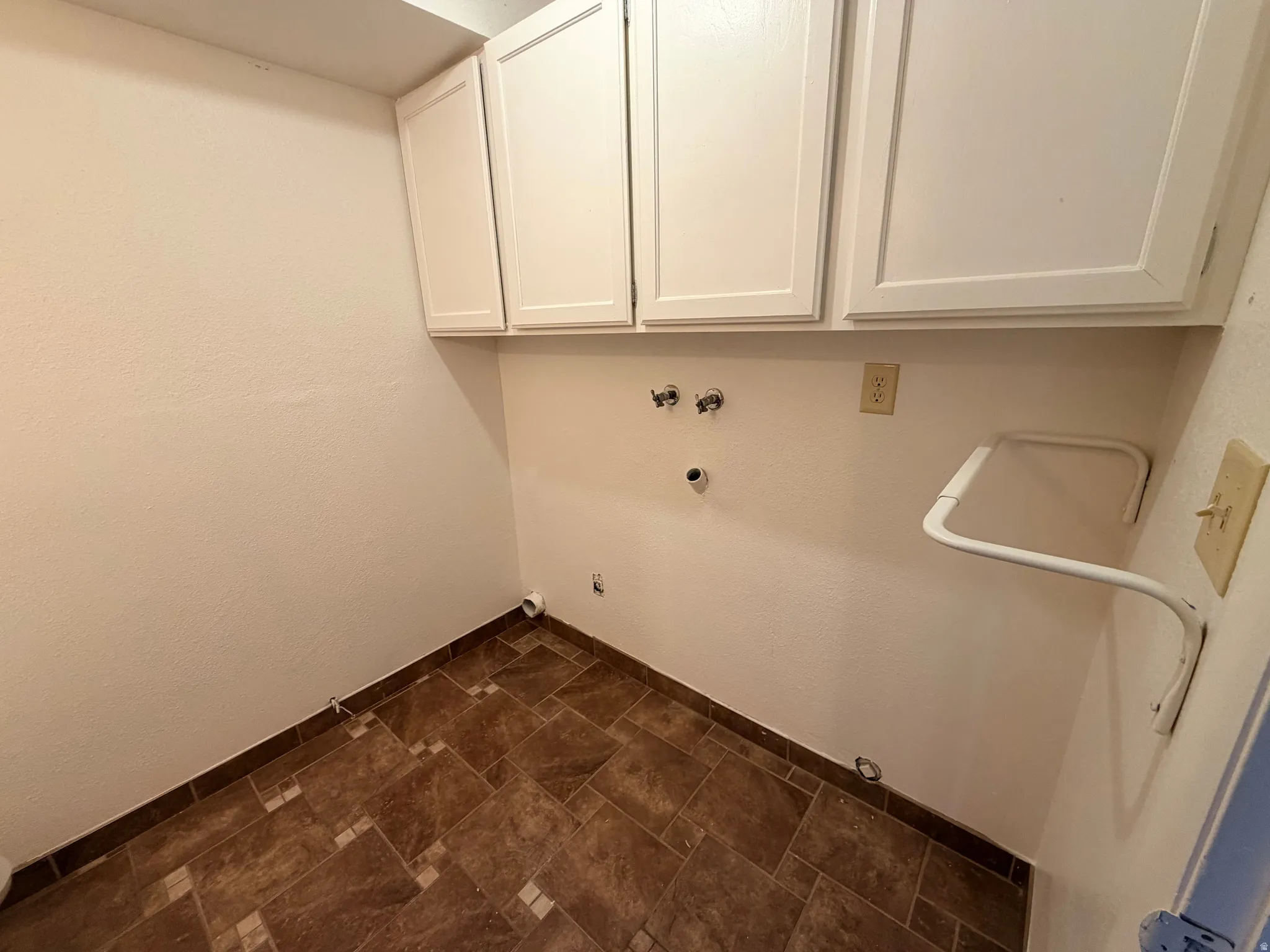 Laundry area featuring hookup for a gas dryer, hookup for a washing machine, cabinet space, and stone finish flooring