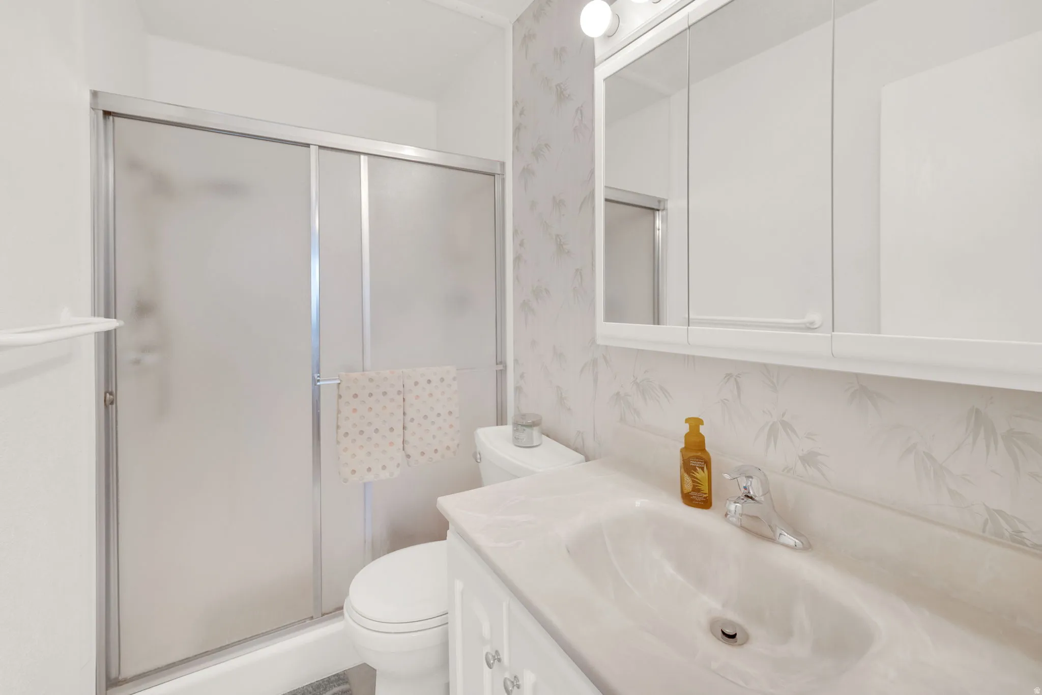 Full bath with vanity, wallpapered walls, and a stall shower