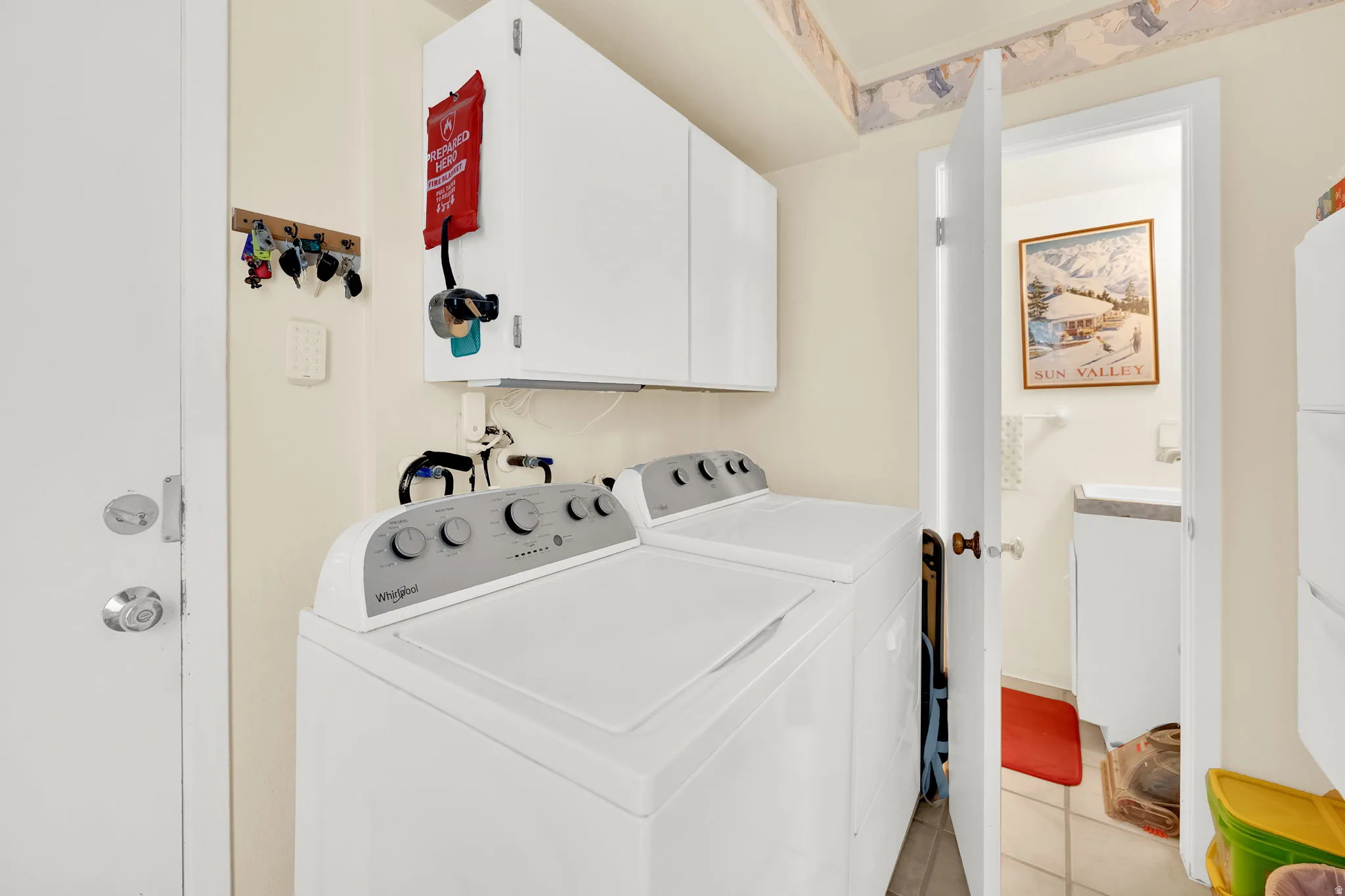Laundry room featuring cabinet space, light tile patterned floors, and washing machine and clothes dryer