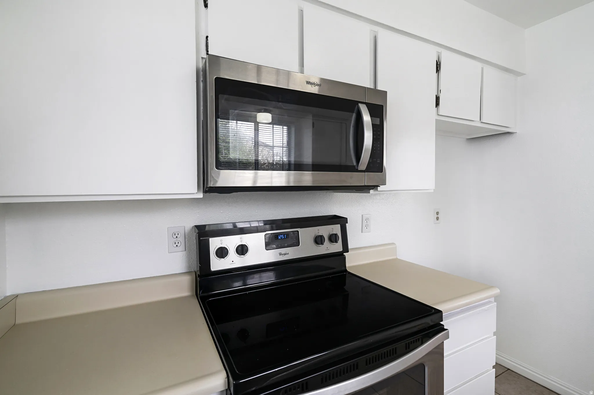 Kitchen featuring stainless steel appliances, white cabinets, and light countertops