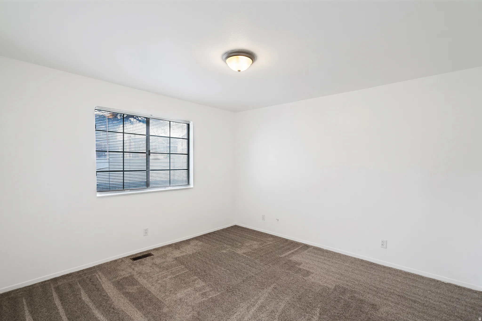 Primary bedroom featuring dark colored carpet and baseboards