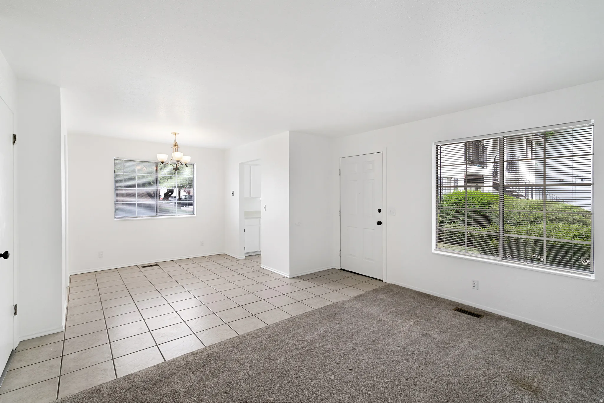 Dining area with a chandelier, light tile patterned flooring, and light colored carpet
