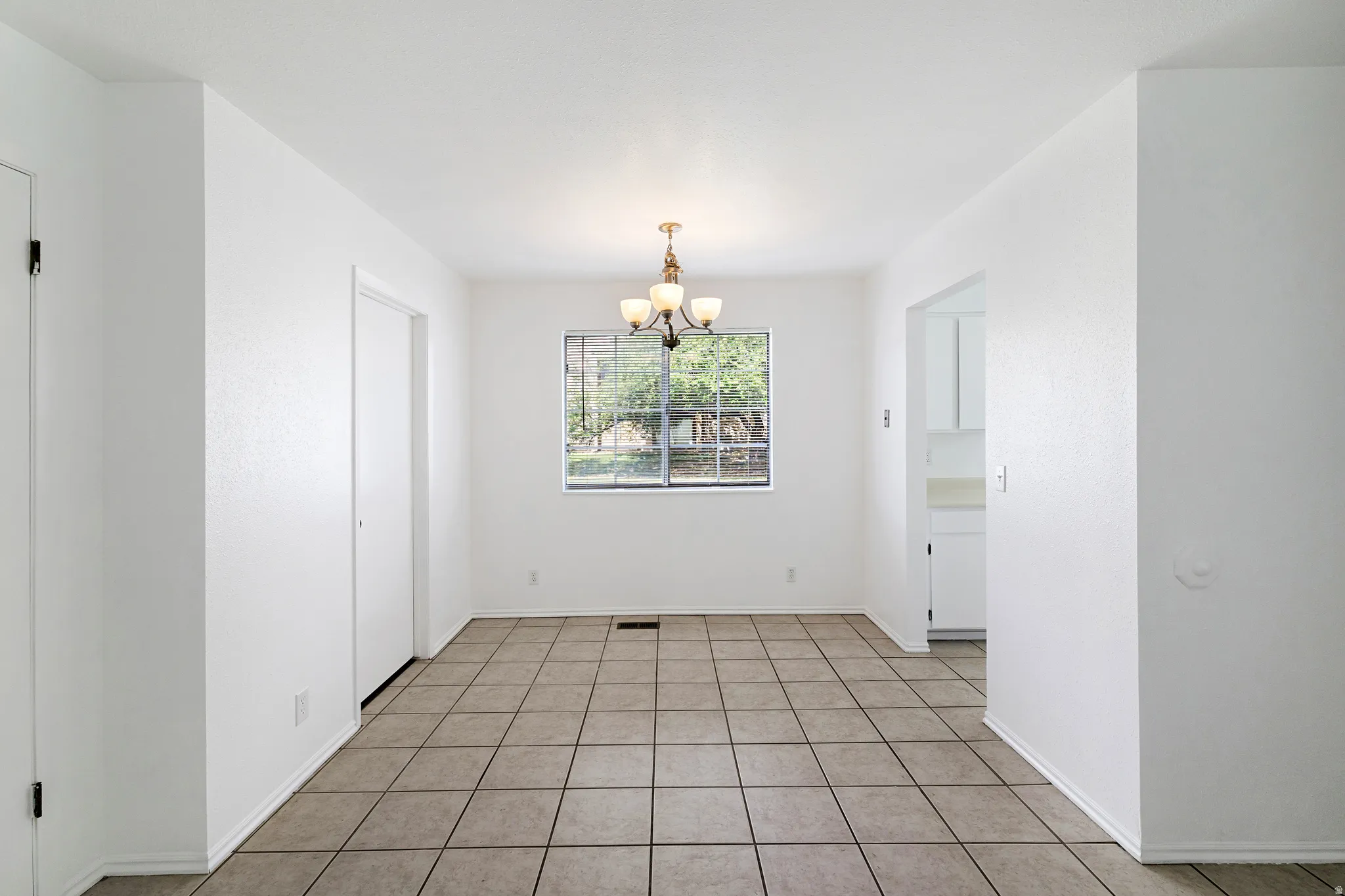 Dining area with suspended lighting and light tile patterned floors