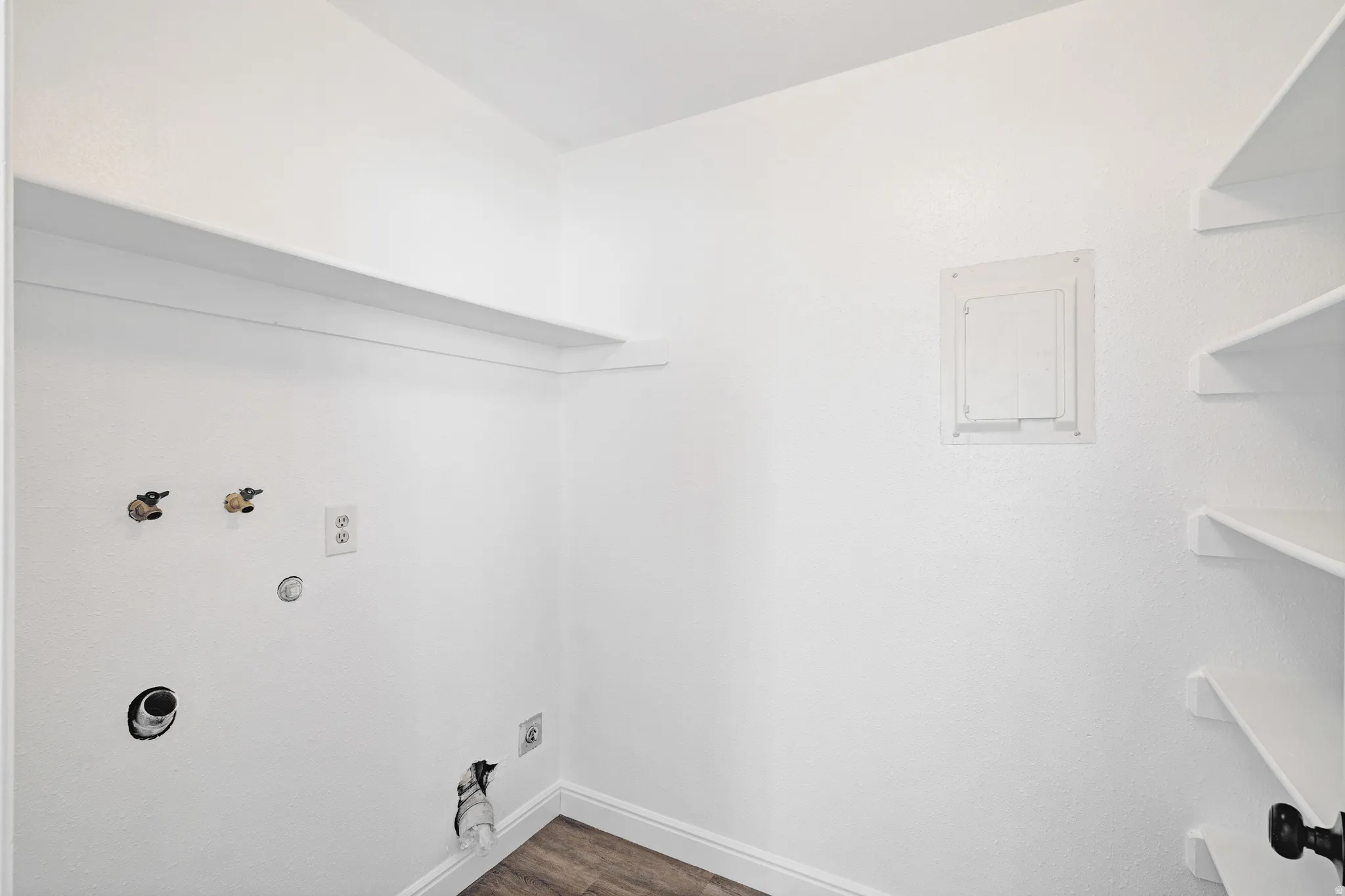 Laundry area featuring hookup for a gas dryer, dark wood finished floors, and hookup for a washing machine. Additional storage shelving.