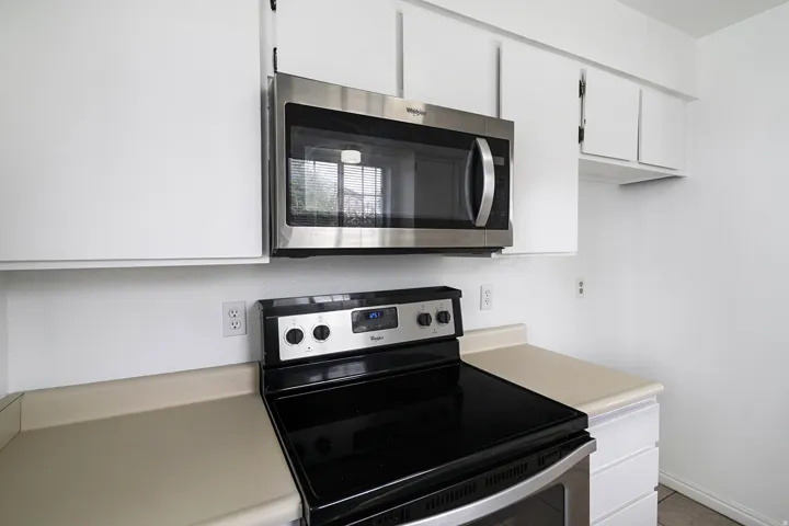 Kitchen featuring stainless steel appliances, white cabinets, and light countertops