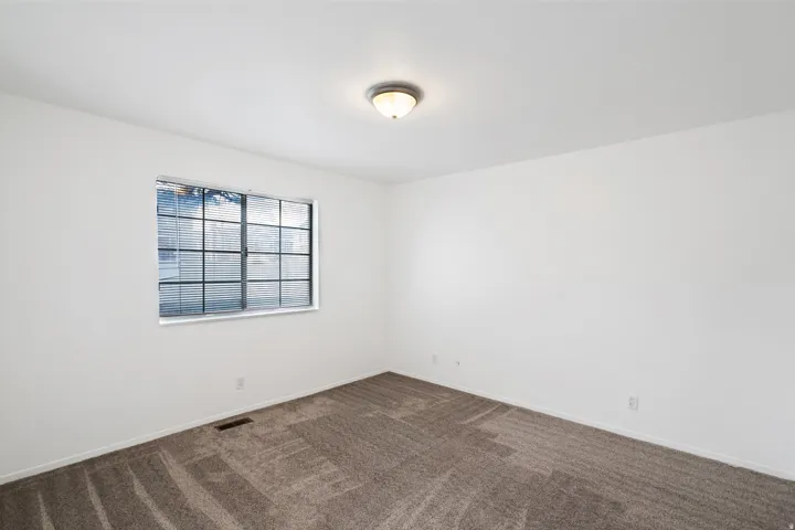Primary bedroom featuring dark colored carpet and baseboards