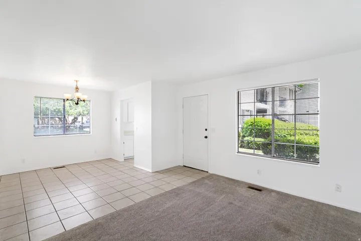 Living room featuring suspended lighting, light tile patterned flooring, and light carpet