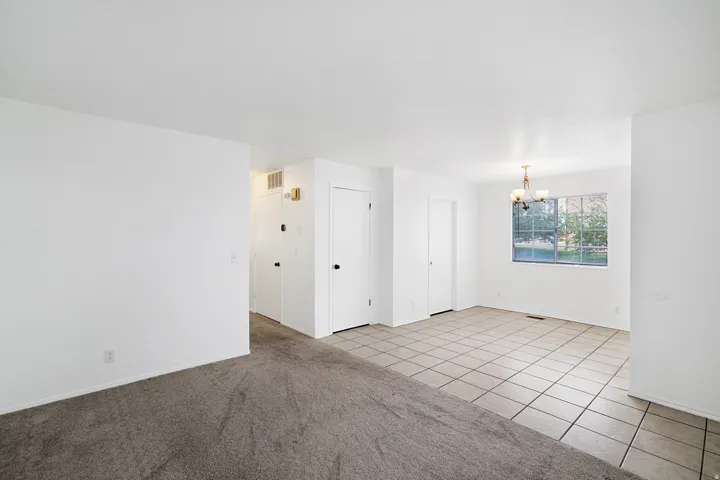 Living room  & dining area featuring suspended lighting, light tile patterned floors, and light carpet