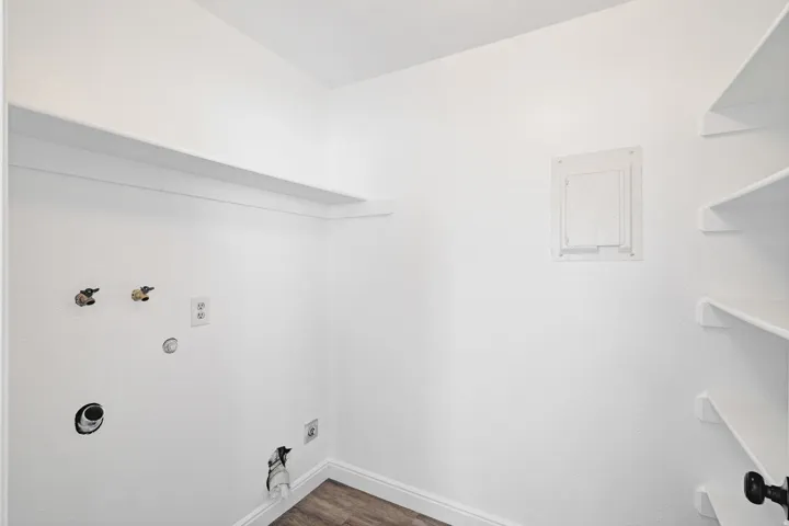 Laundry area featuring hookup for a gas dryer, dark wood finished floors, and hookup for a washing machine. Additional storage shelving.