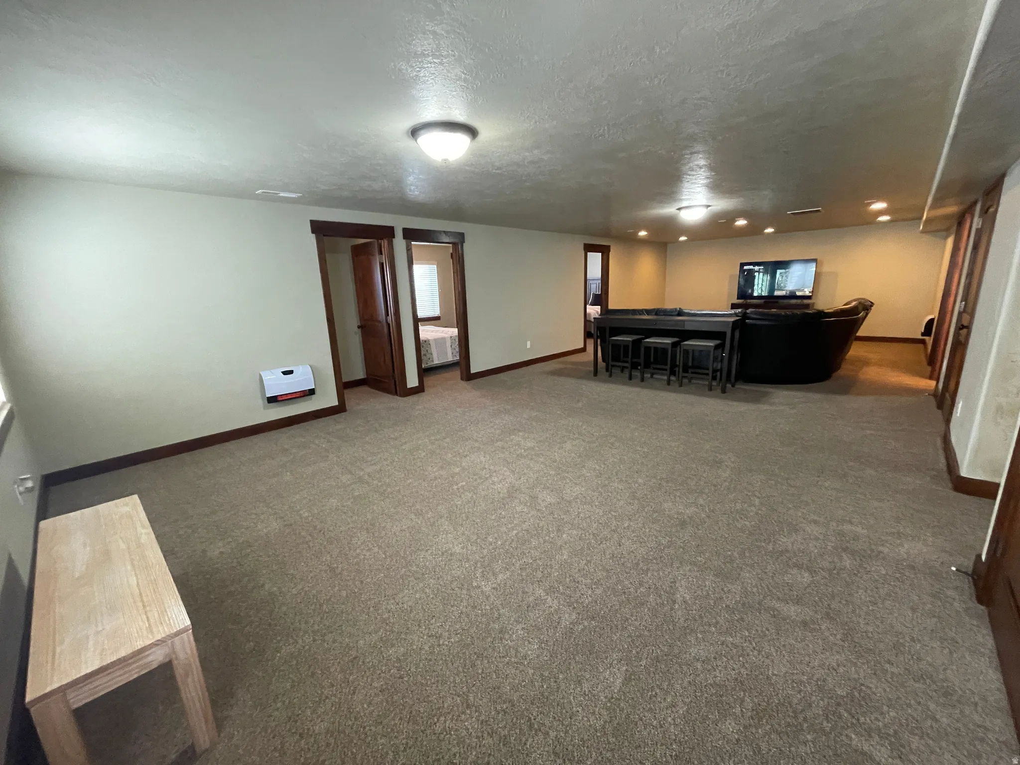 Living area with dark colored carpet and a textured ceiling