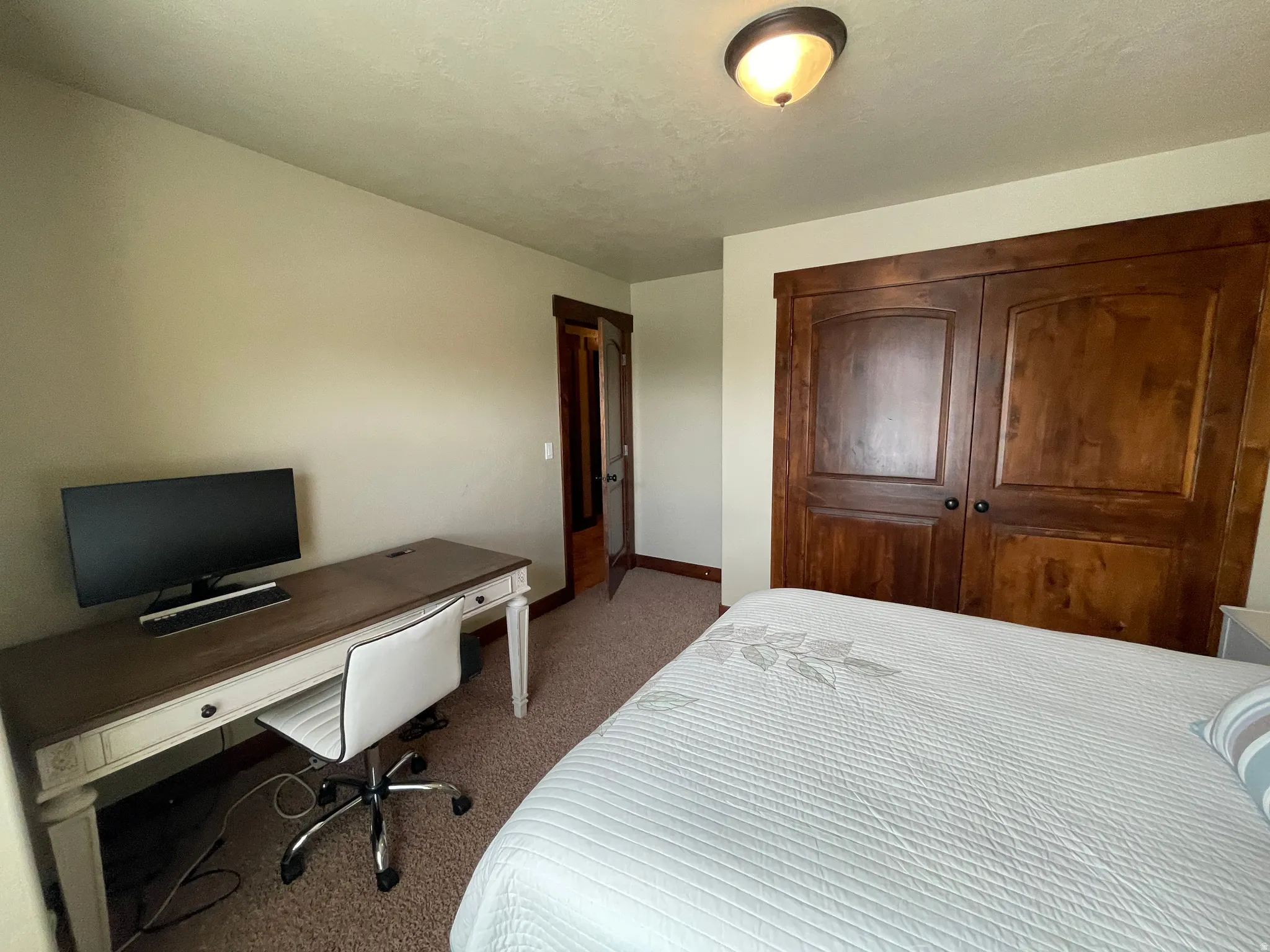 Bedroom featuring an office area, dark colored carpet, and a closet