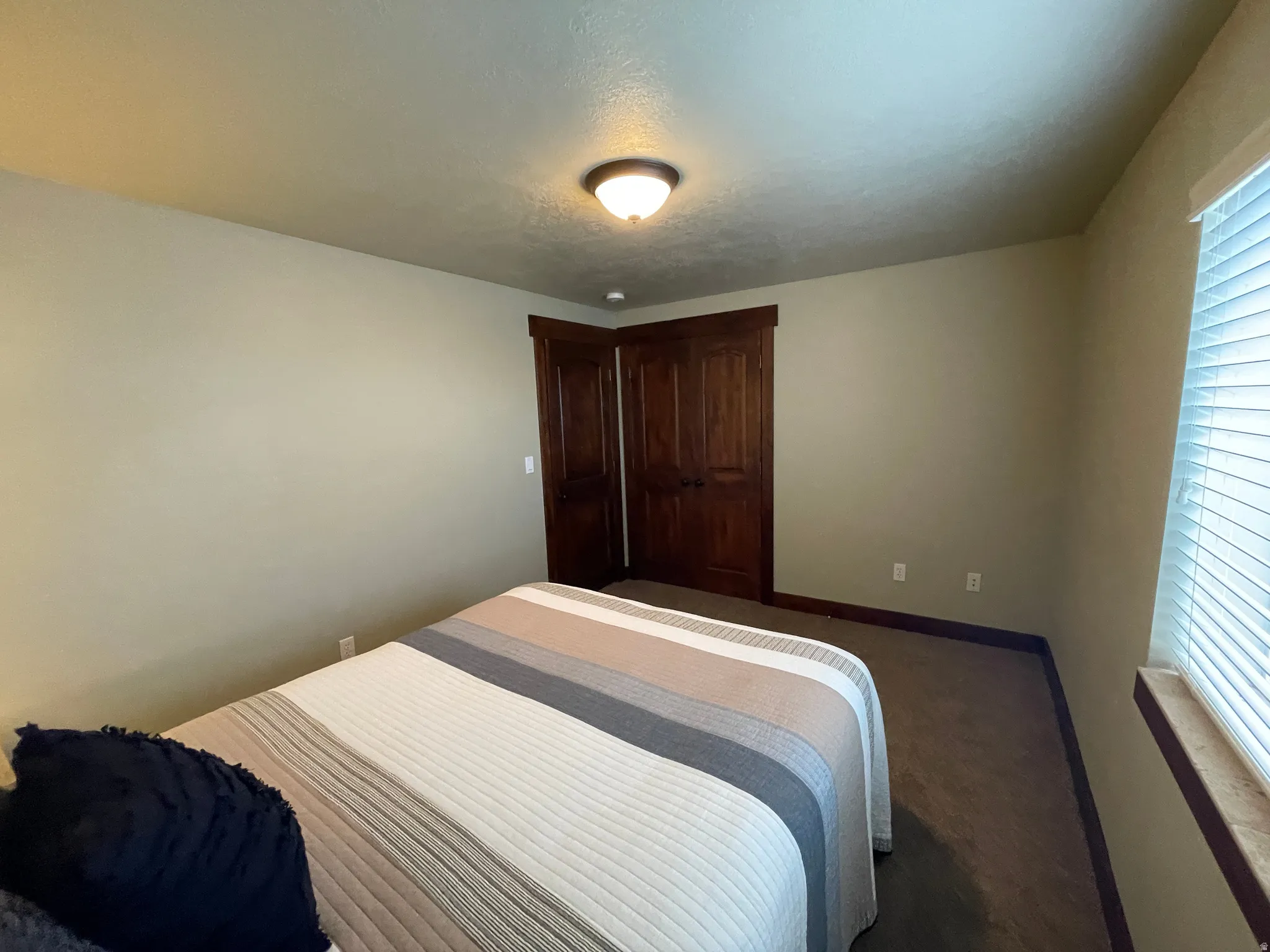 Bedroom featuring baseboards and dark carpet