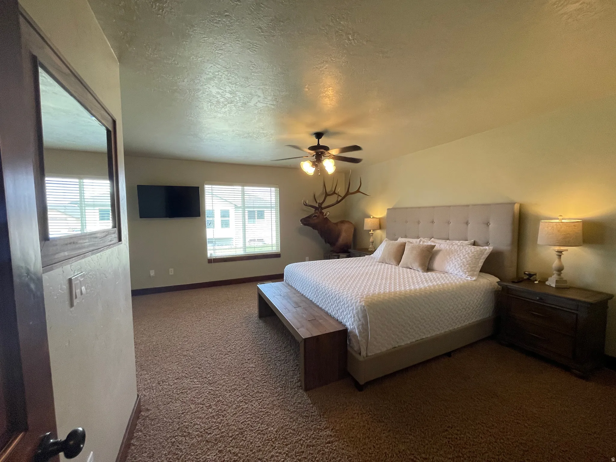 Bedroom featuring a textured ceiling, dark carpet, and ceiling fan