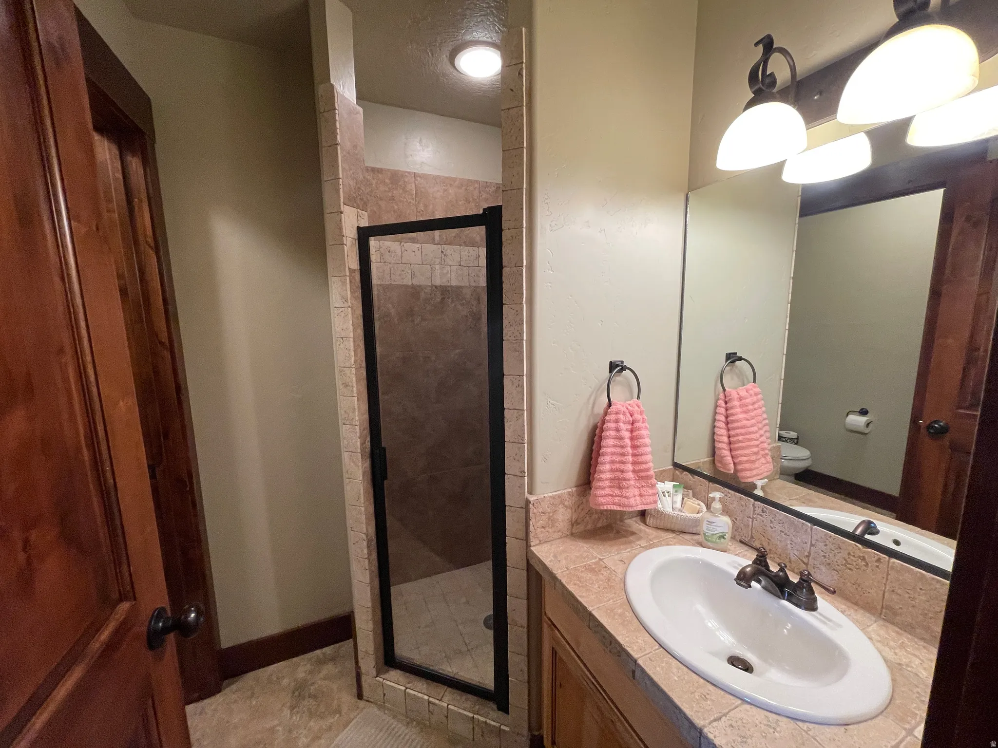Full bathroom featuring vanity, a shower stall, and a textured ceiling