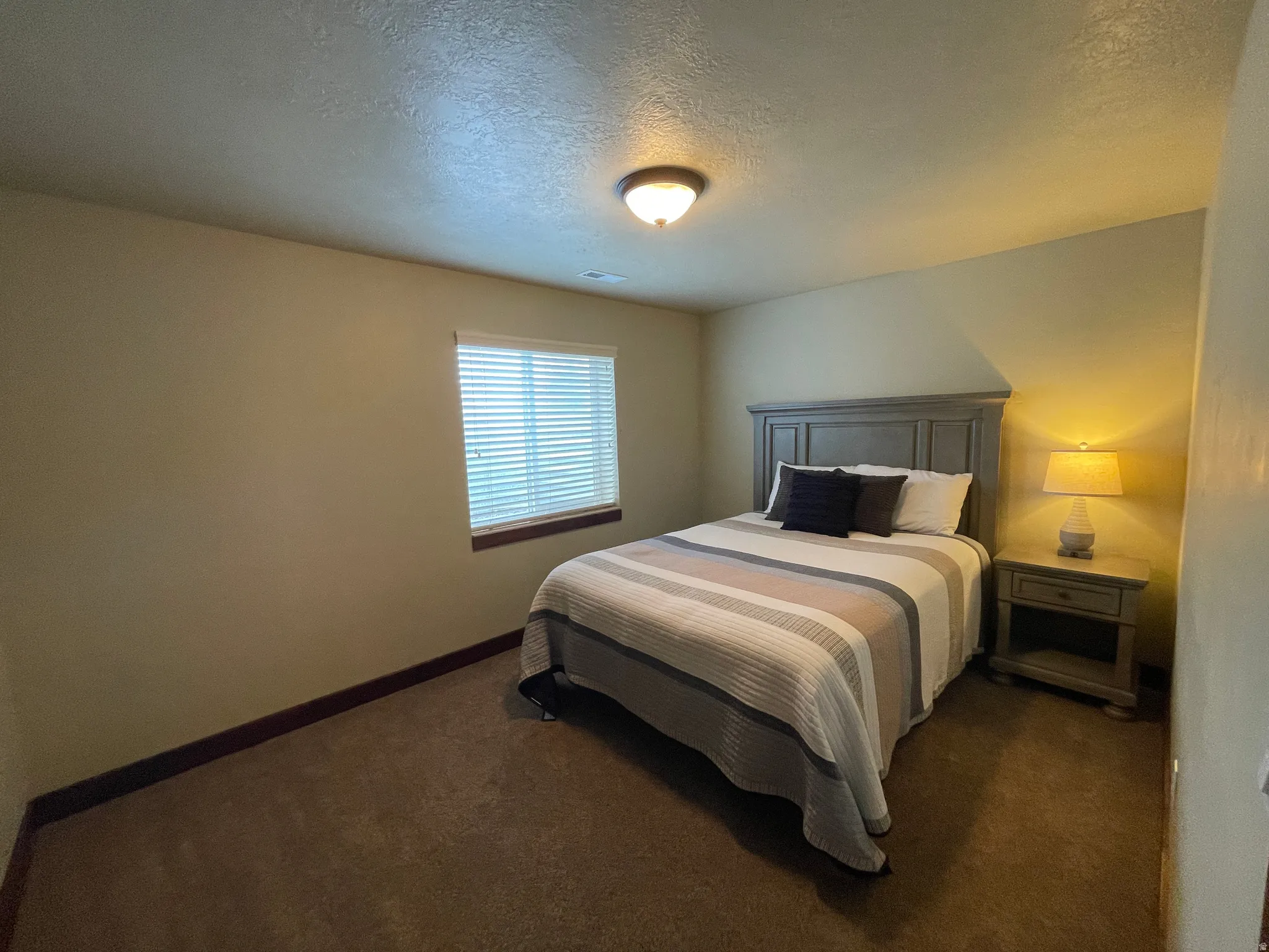 Bedroom with a textured ceiling and dark colored carpet