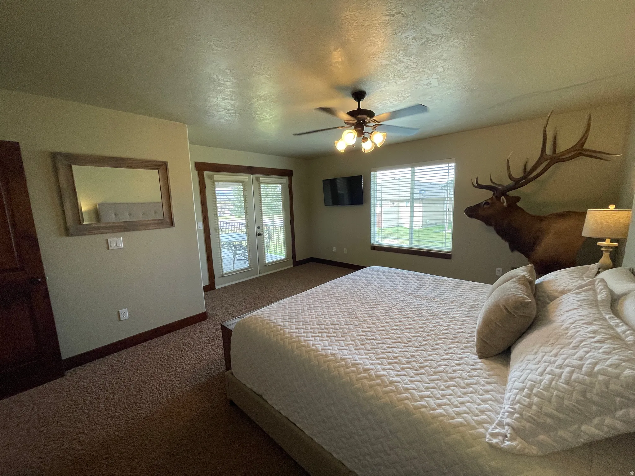 Bedroom with a textured ceiling, access to outside, dark carpet, ceiling fan, and french doors
