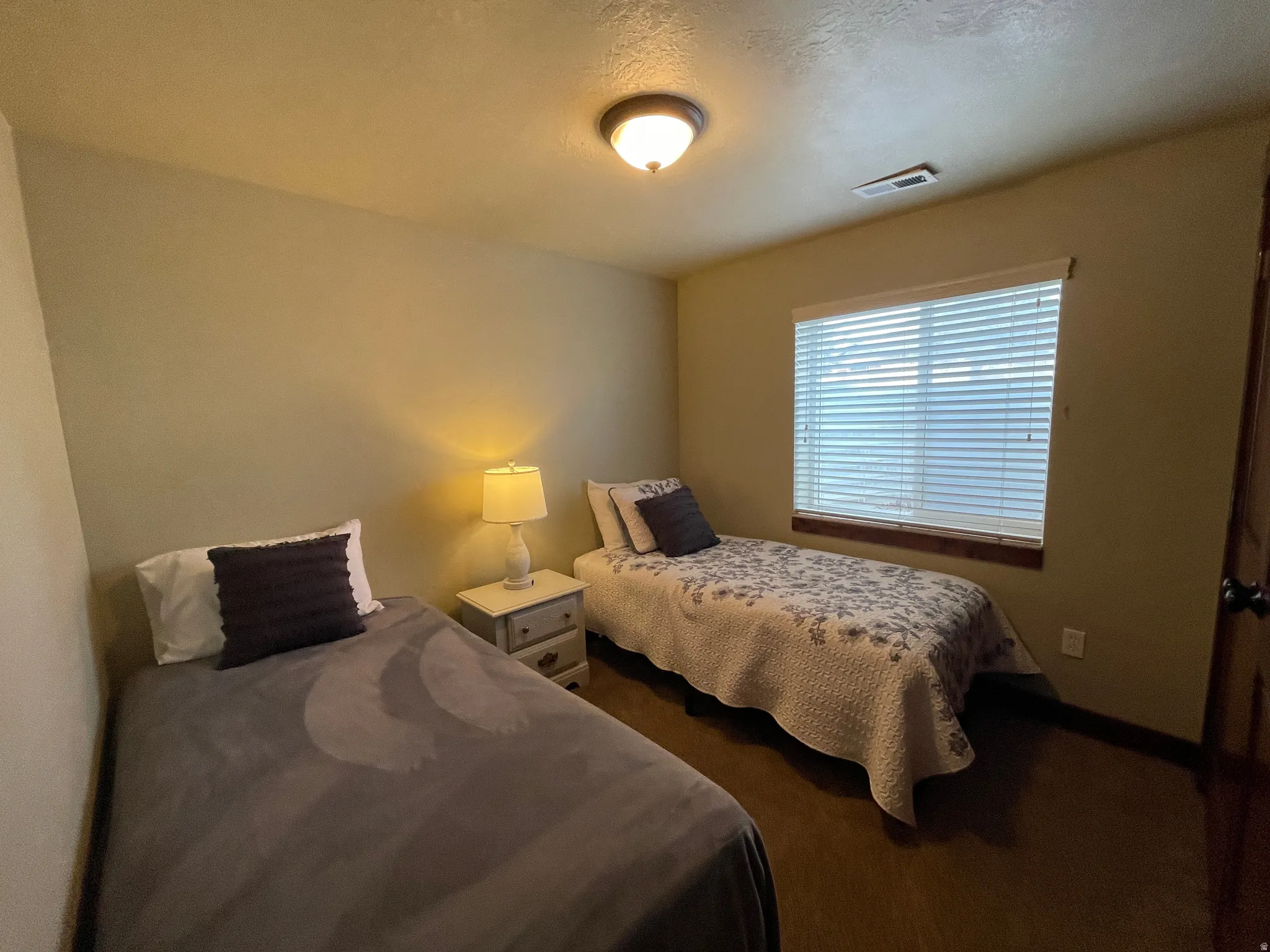 Bedroom featuring dark carpet and a textured ceiling