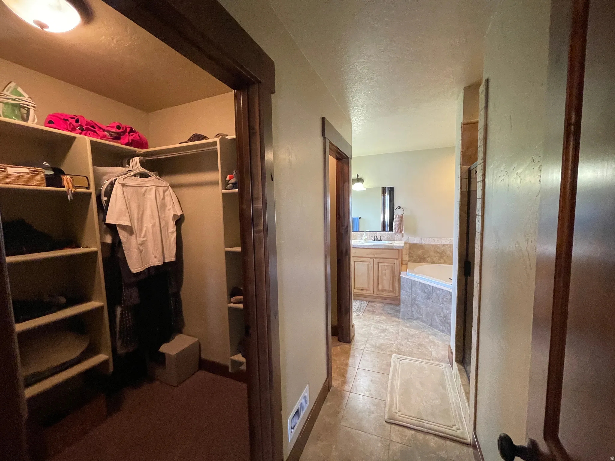 Full bath with a garden tub, vanity, a shower stall, light tile patterned floors, and a textured ceiling