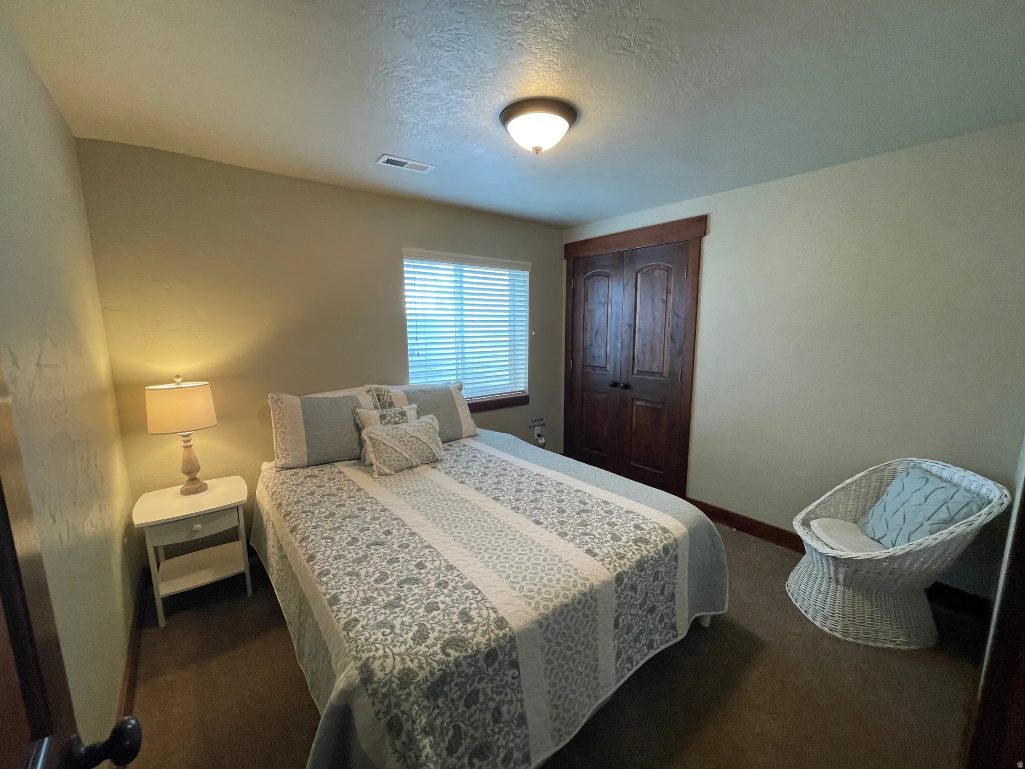Bedroom with a textured ceiling and dark carpet