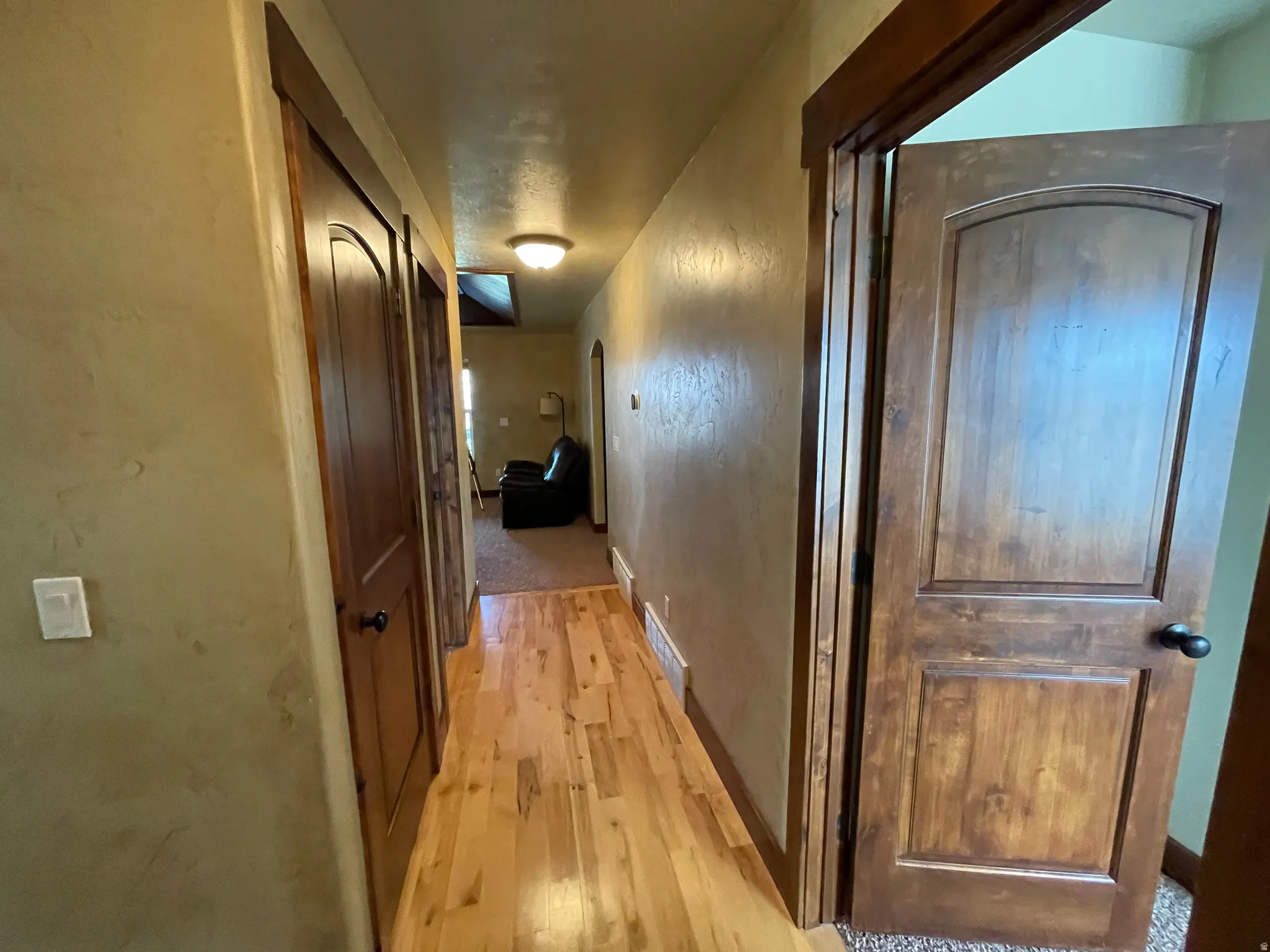 Corridor featuring light wood-type flooring and a textured wall