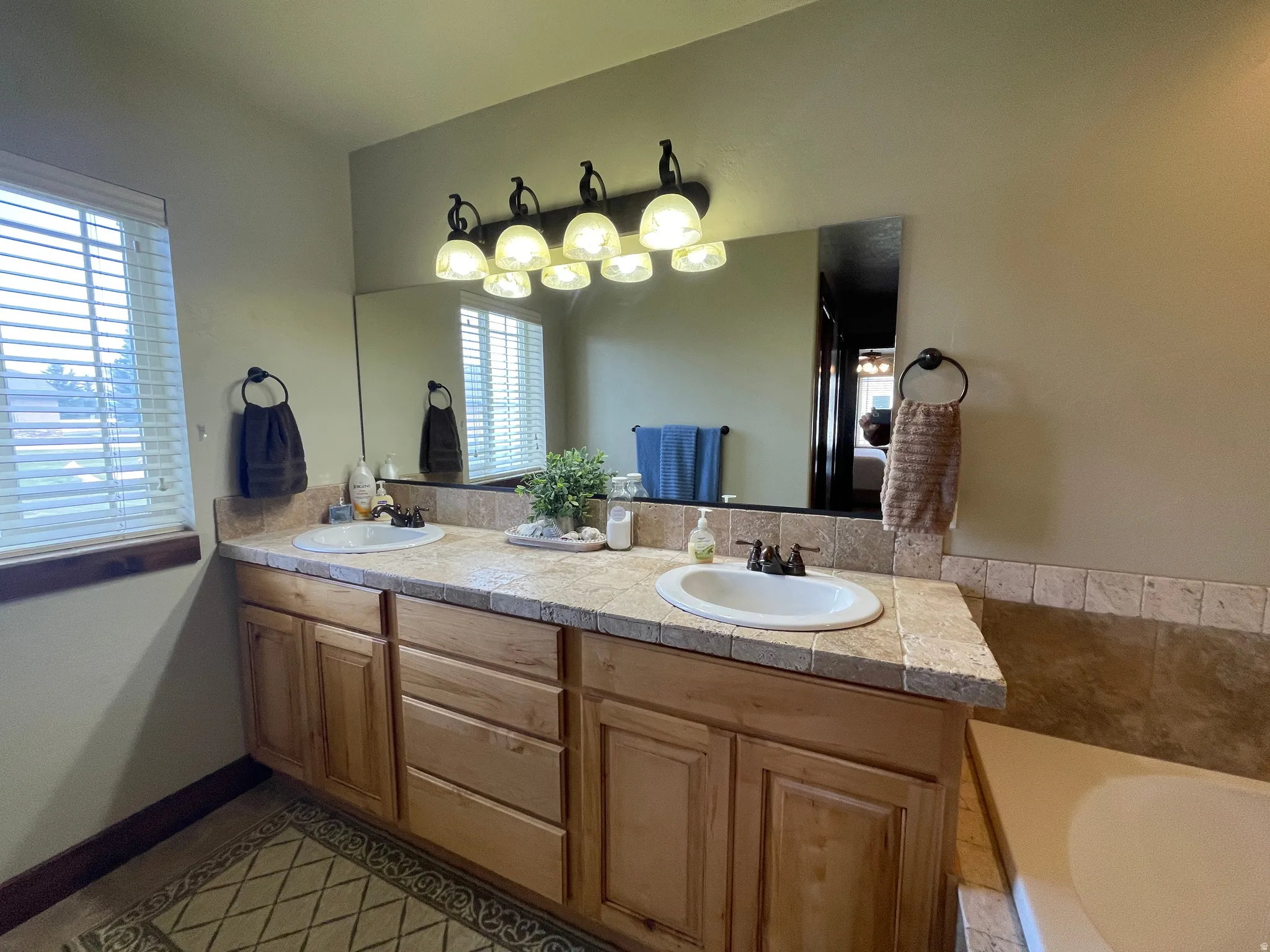 Bathroom featuring double vanity, light tile patterned floors, and a bath