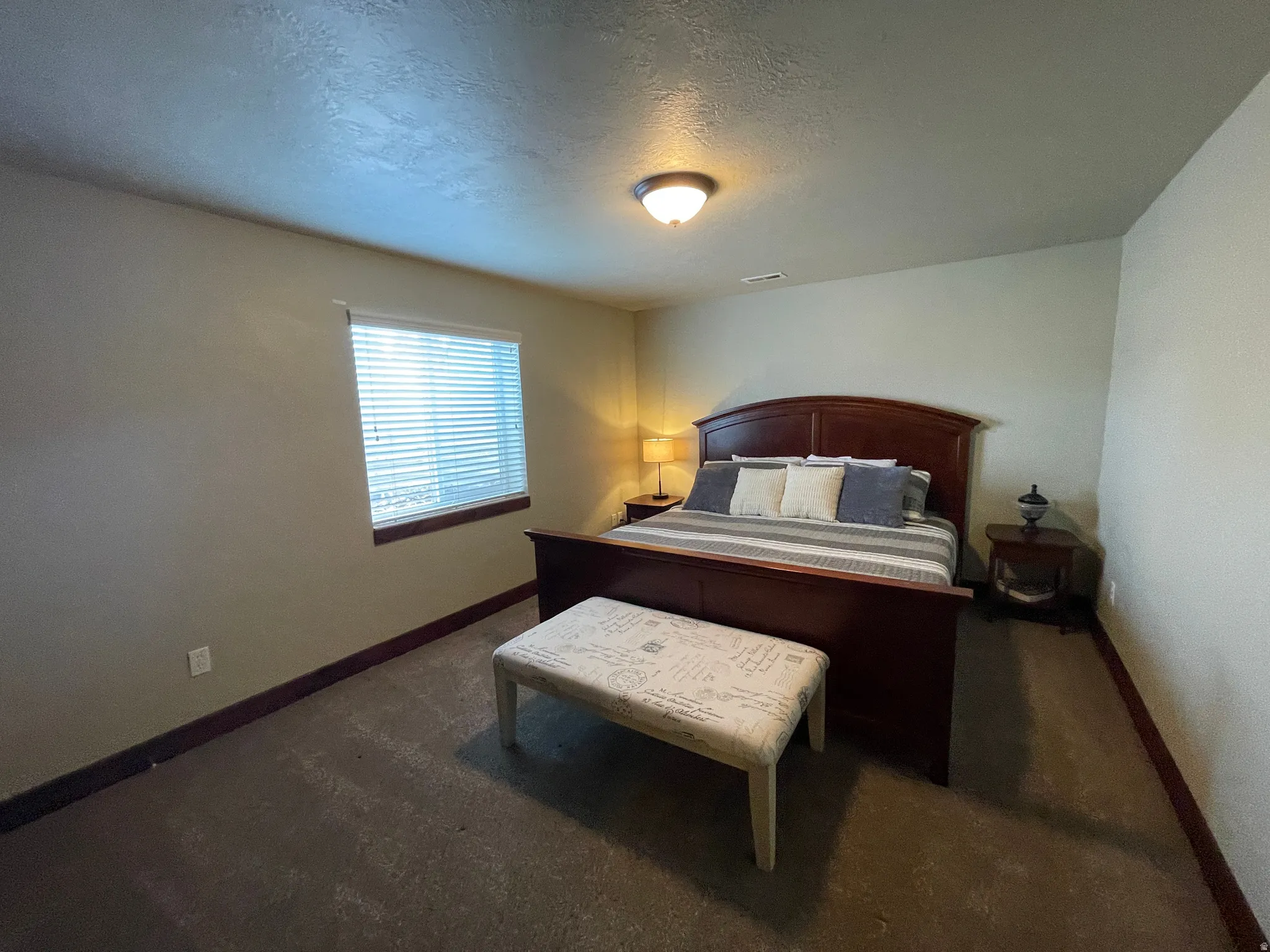 Bedroom with a textured ceiling and dark carpet