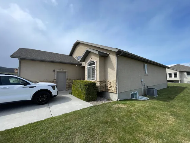 View of side of home with stucco siding and a lawn