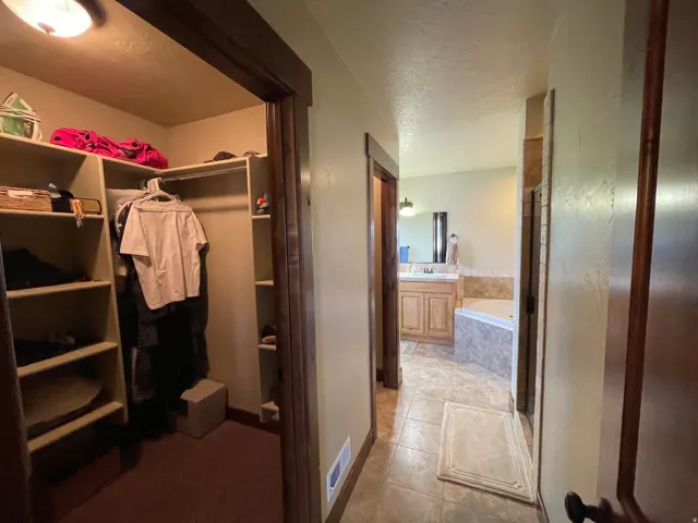 Full bath with a garden tub, vanity, a shower stall, light tile patterned floors, and a textured ceiling