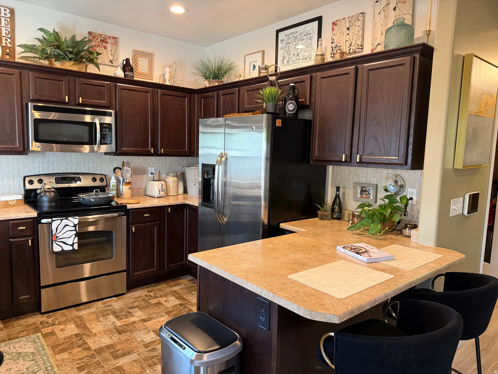 Kitchen with dark wood finish cabinetry, stainless steel appliances, a kitchen breakfast bar, and backsplash