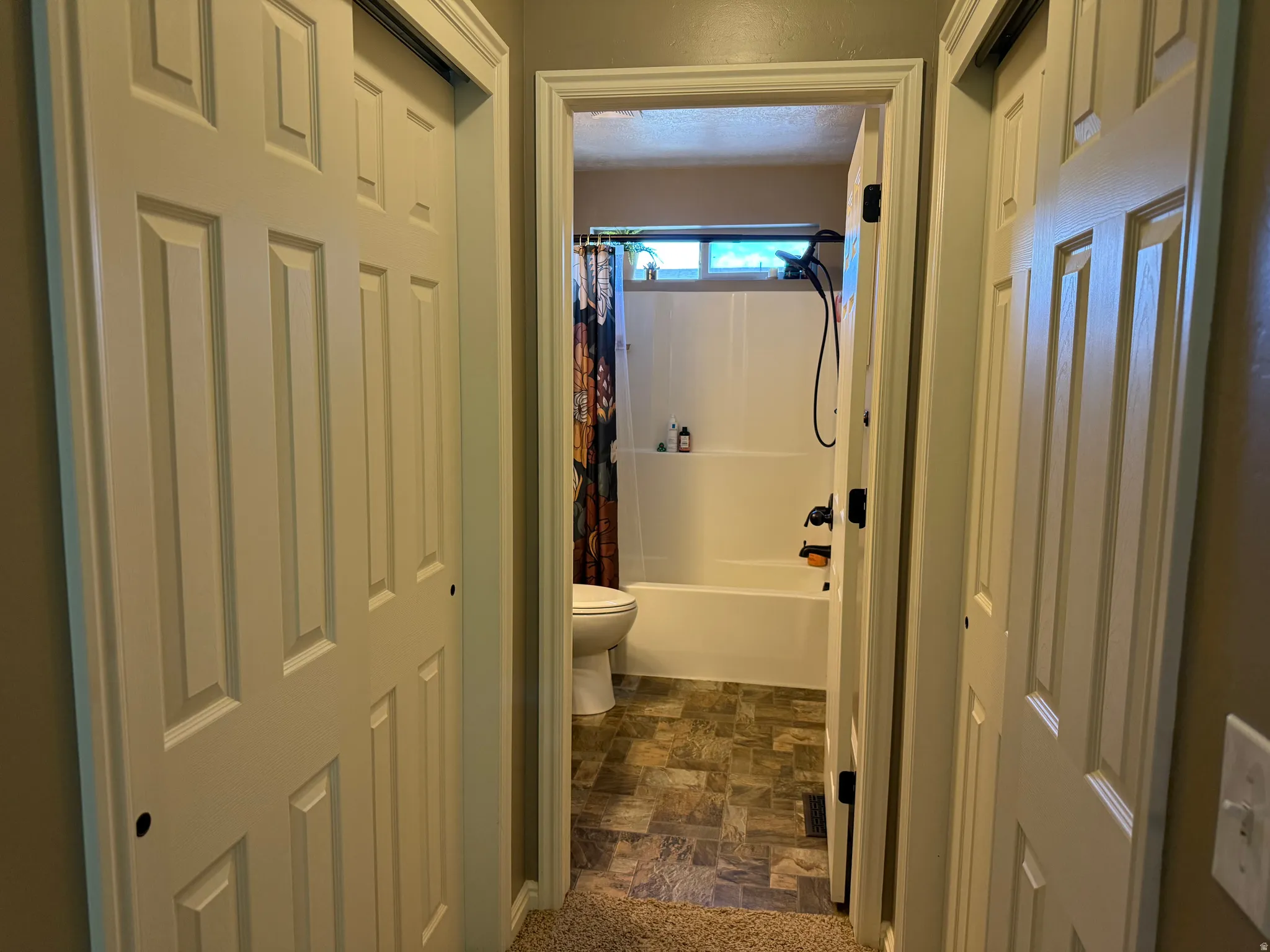 Full bath featuring stone finish floors and shower / tub combo with curtain