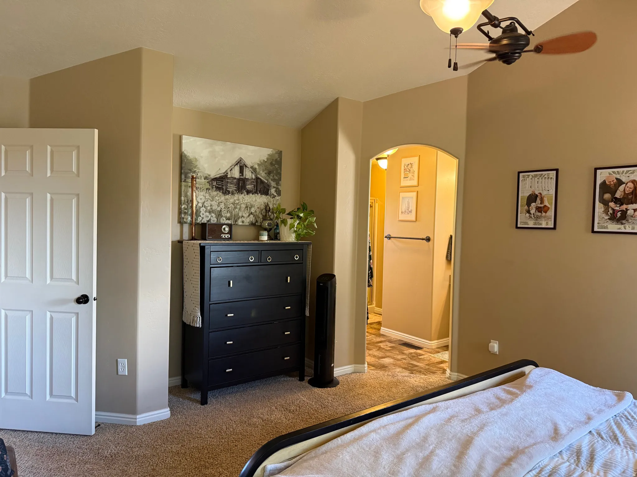 Bedroom featuring arched walkways, light colored carpet, and ceiling fan