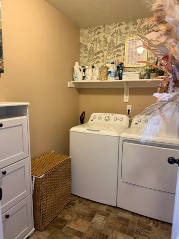 Laundry room with stone finish floors, independent washer and dryer, and a textured ceiling