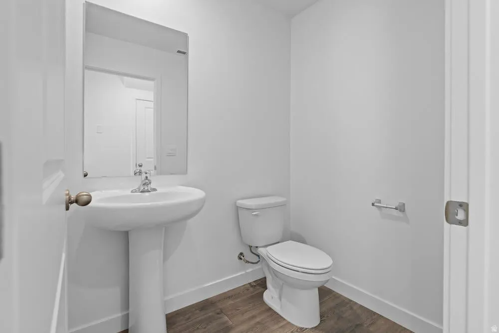 Half bathroom featuring toilet and dark wood-style floors