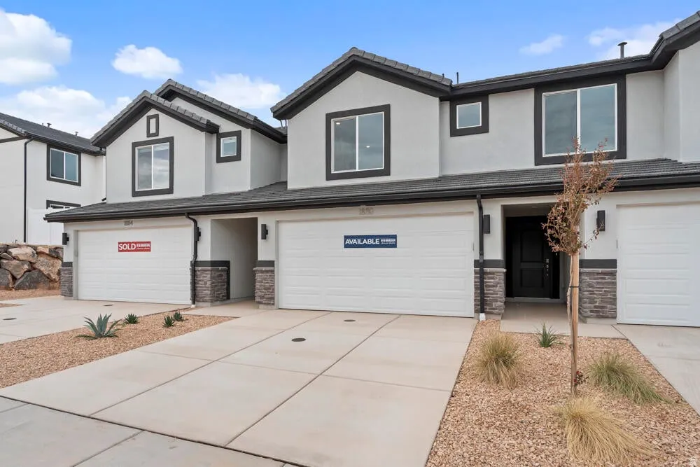 Traditional home with stone siding, stucco siding, an attached garage, concrete driveway, and a tiled roof