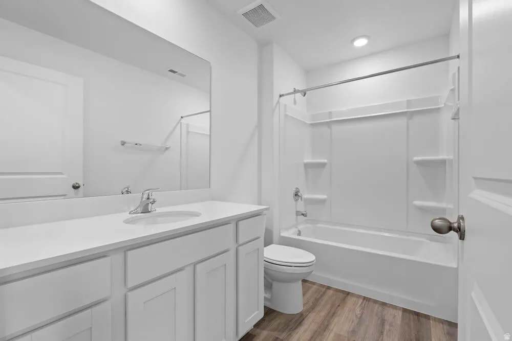 Bathroom with light wood-type flooring, vanity, and shower / washtub combination