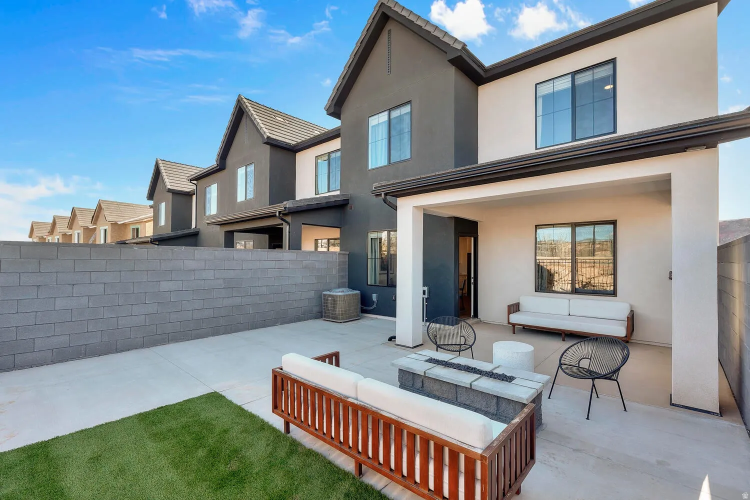 Rear view of house with stucco siding, a patio area, a fenced backyard, and an outdoor lounge area