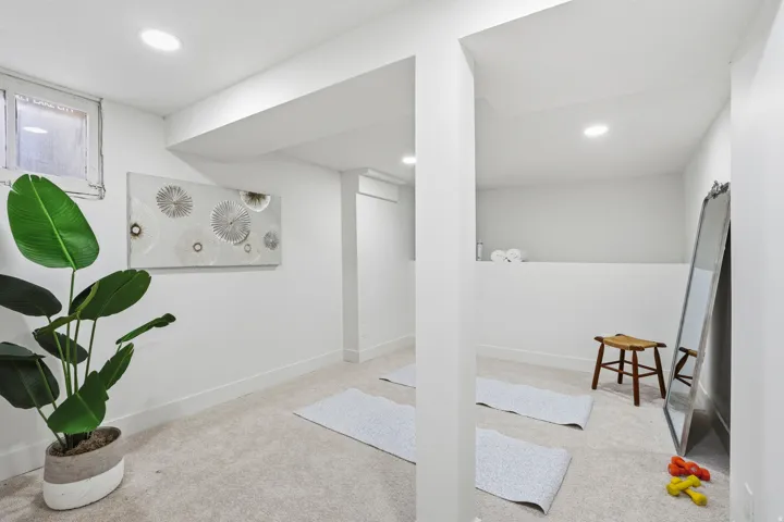 Finished below grade area with light colored carpet and recessed lighting